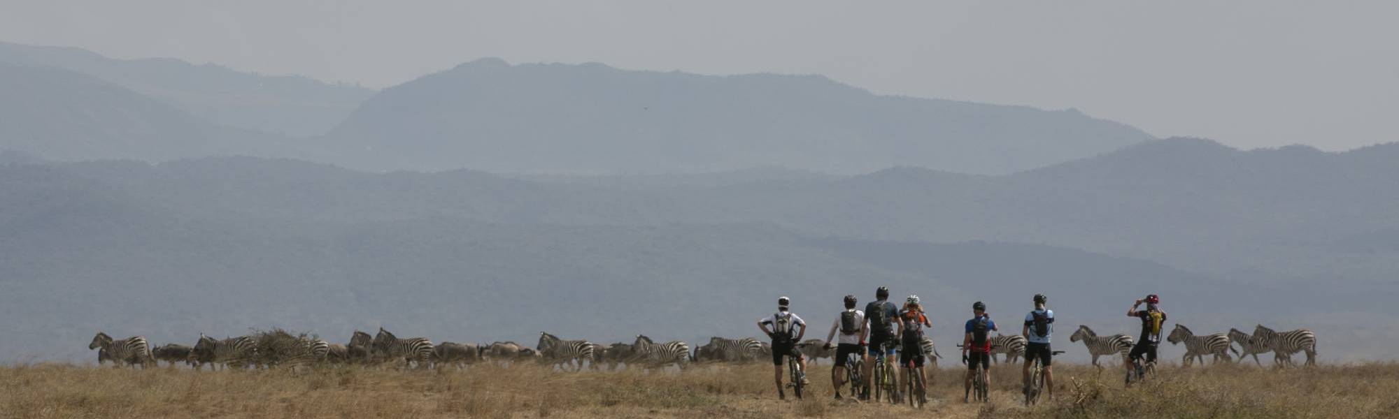 Deelnemer Africa Classic steekt zijn duim op tijdens het fietsen op een dirt road