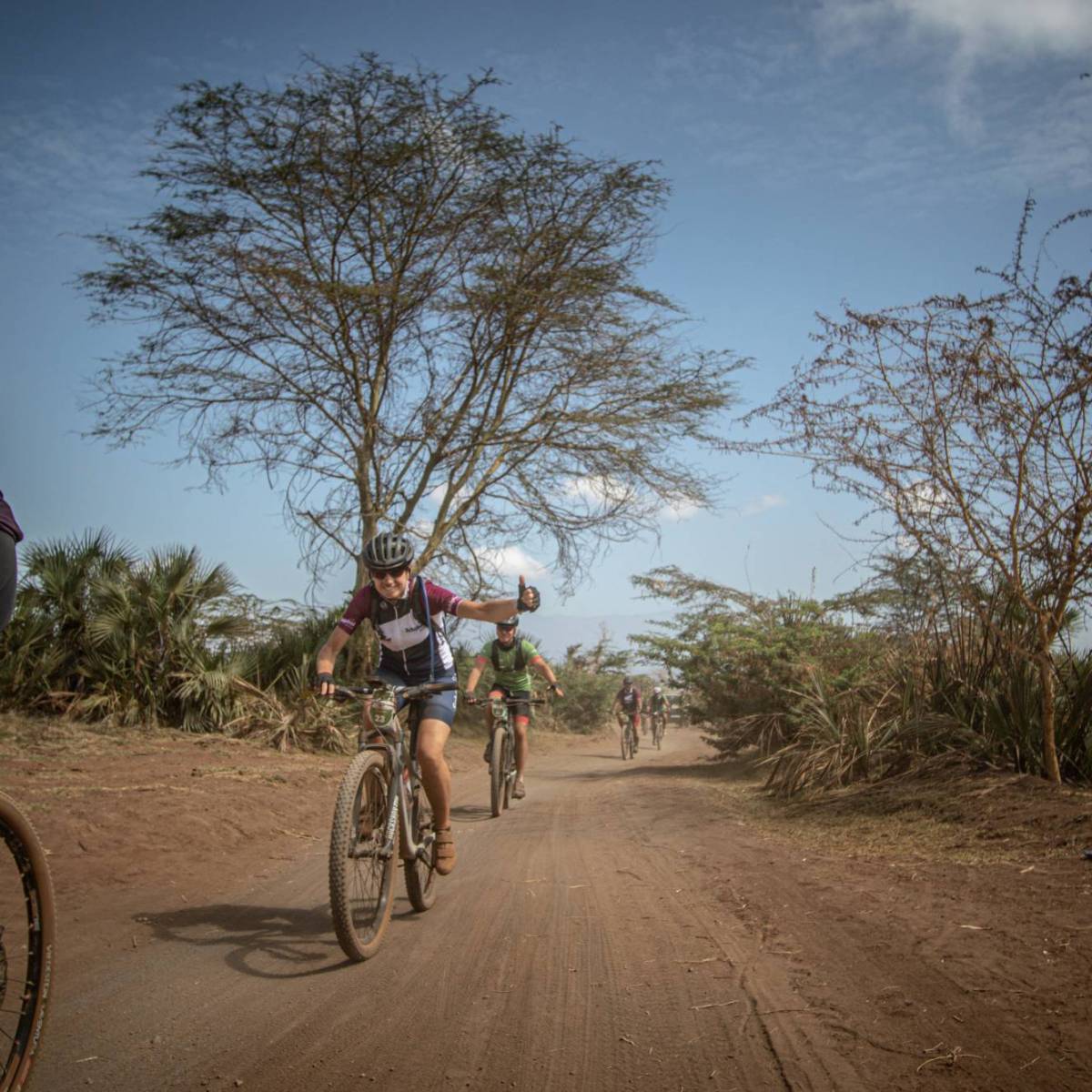 Deelnemers van Africa Classic fietsen over een weg in de savanne