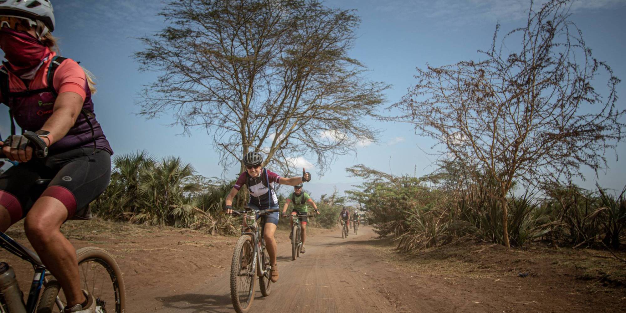 Deelnemers van Africa Classic fietsen over een weg in de savanne