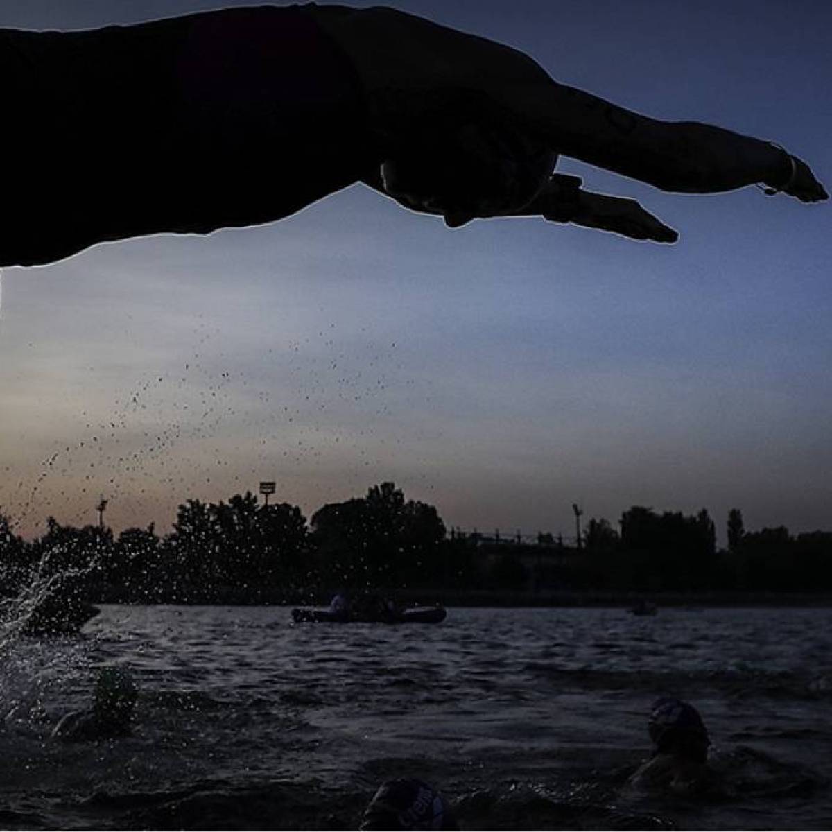 Triatleet die van start gaat met het eerste onderdeel door het water in te duiken