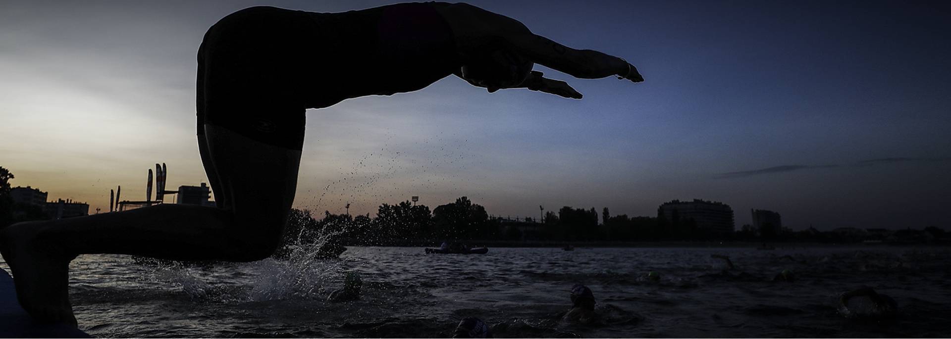 Triatleet die van start gaat met het eerste onderdeel door het water in te duiken