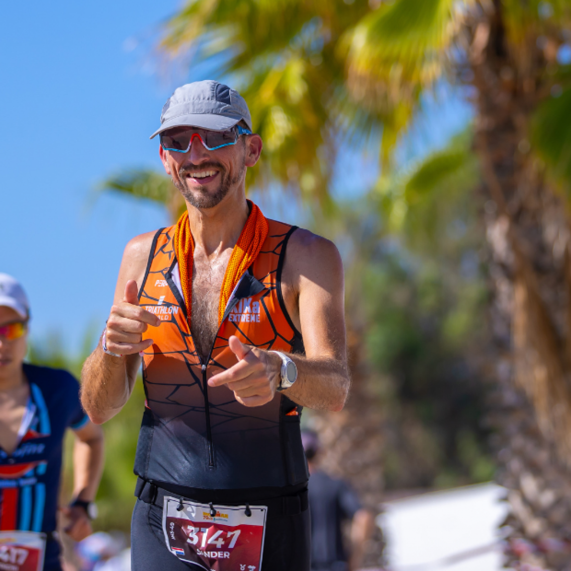 Triatleten die in een wetsuit en oranje badmutsen het water in rennen