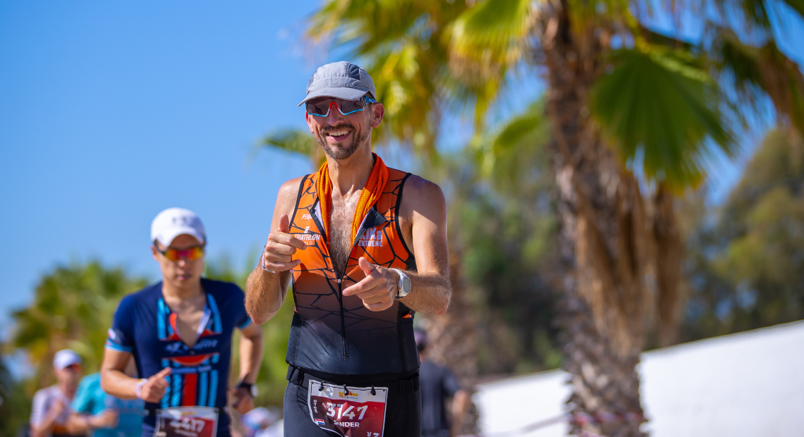 Triatleten die in een wetsuit en oranje badmutsen het water in rennen